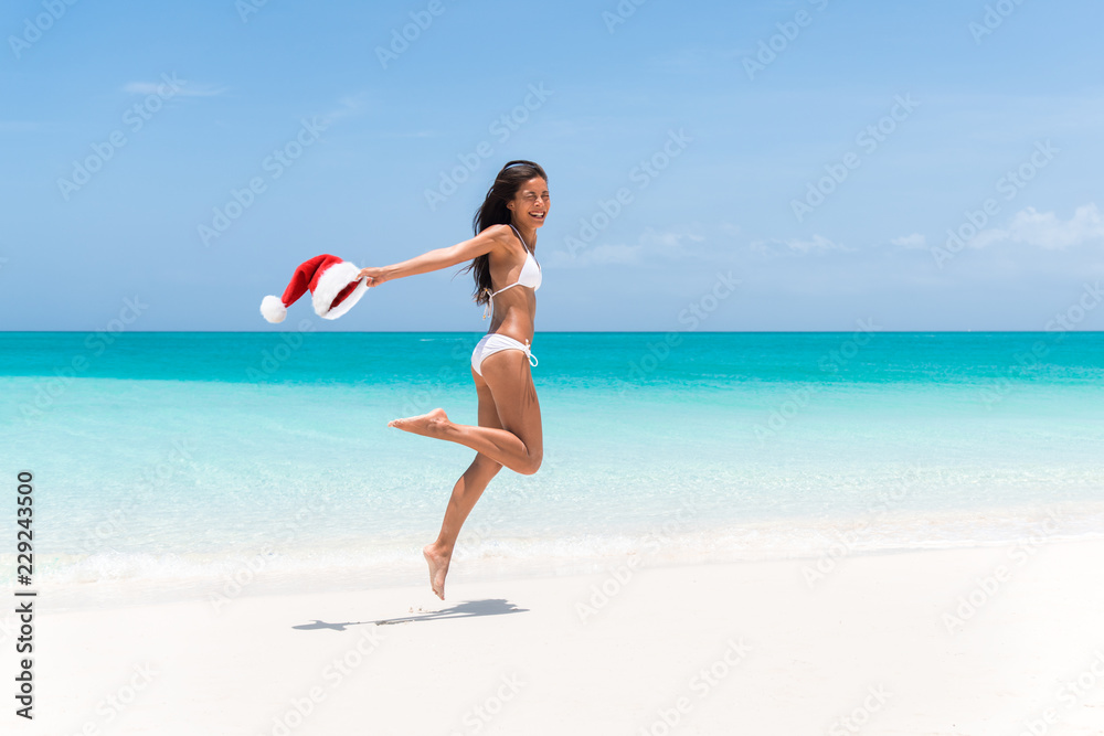 Christmas holiday at the Caribbean beach. Happy funny woman jumping of joy for weight loss or laser treatment with Santa Claus hat. Paradise winter vacation in the south, sexy bikini body girl. Christmas holiday at the Caribbean beach. Happy funny woman jumping of joy for weight loss or laser treatment with Santa Claus hat. Paradise winter vacation in the south, sexy bikini body girl.