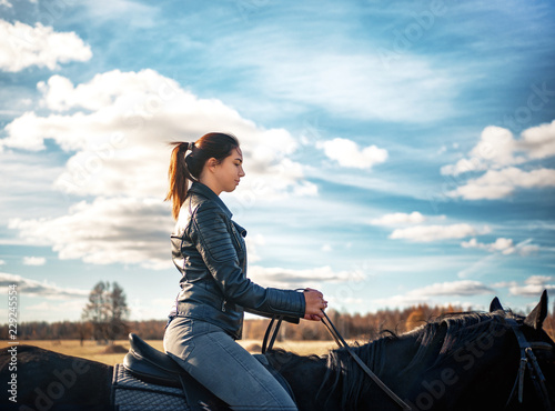 Russian Girl rides a black horse on a Sunny day © Михаил Гужов