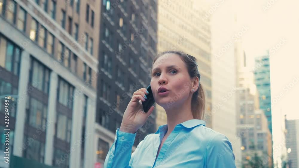 Attractive Caucasian female businesswoman office worker talking on the phone in NYC financial district, skyscrapers in the background. 4K UHD Attractive Caucasian female businesswoman office worker talking on the phone in NYC financial district, skyscrapers in the background. 4K UHD