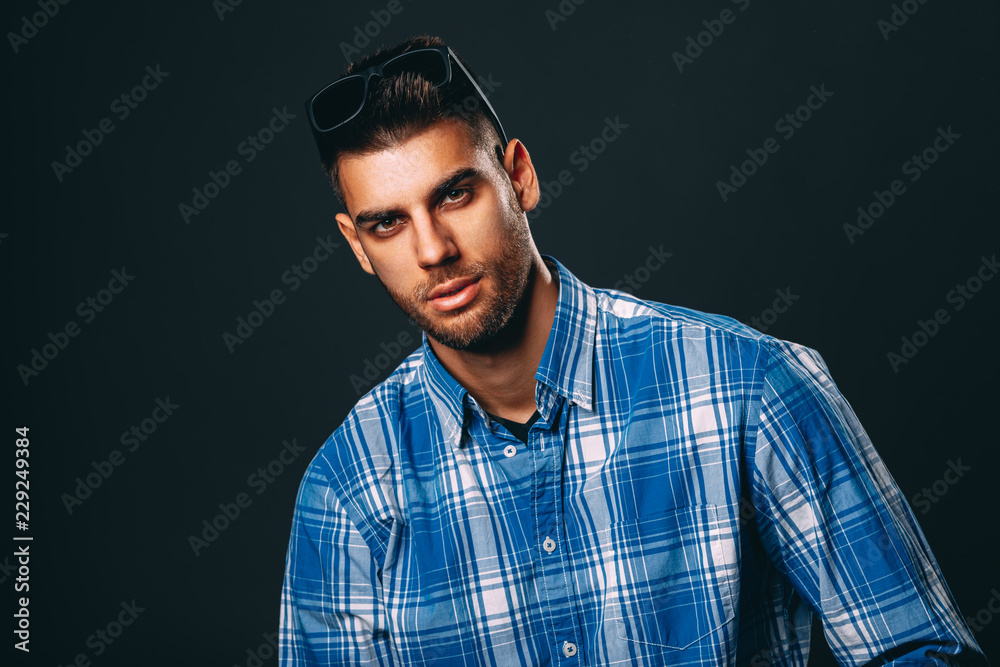 Handsome man with sunglasses posing in studio on dark background Handsome man with sunglasses posing in studio on dark background
