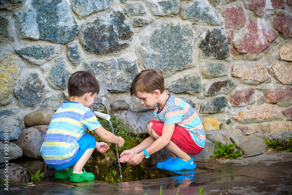 the boy drinks cold water outdoors from the pipe the boy drinks cold water outdoors from the pipe