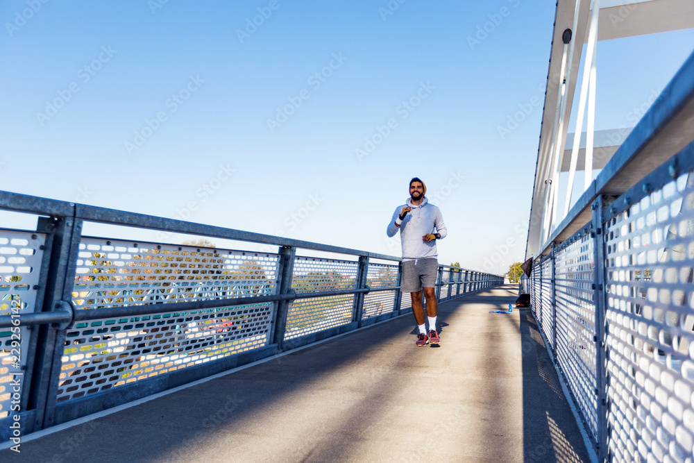 Young male jogger running at bridge