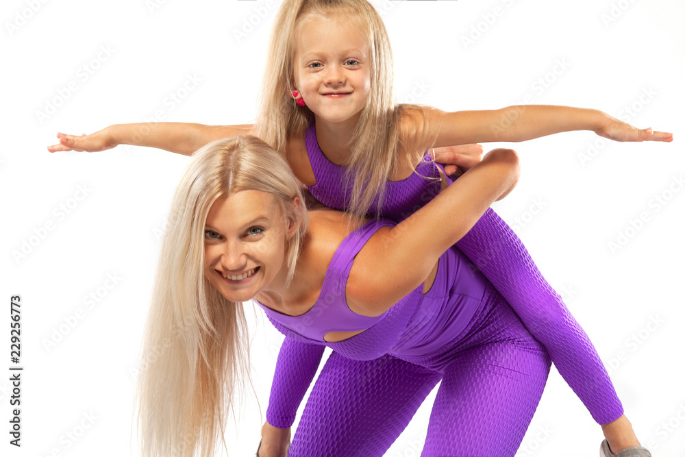 Mother's day concept. Young mother and daughter exercise fitness together indoors. Family look. Mother's day concept. Young mother and daughter exercise fitness together indoors. Family look.