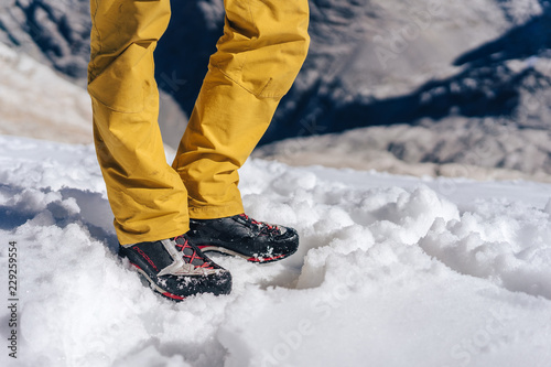 Detail close up shot of hiking or trekking shoes on snow. Technical outdoor boots on a glacier. Mountaineering or climbing winter shoes product photo.