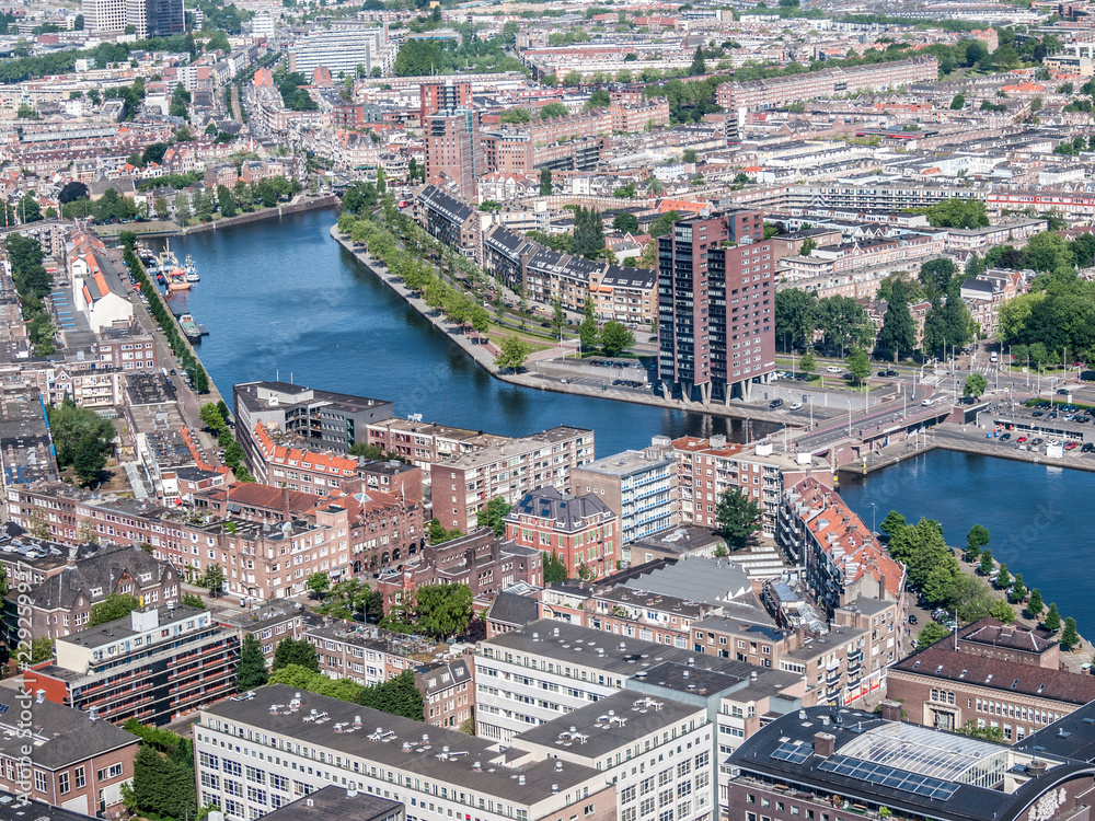 Obraz premium Aerial urban panoramic landscape of buildings, canals, bridges and small green areas with trees of Rotterdam big business city, calm blue water, sunny day in South Holland, Netherlands