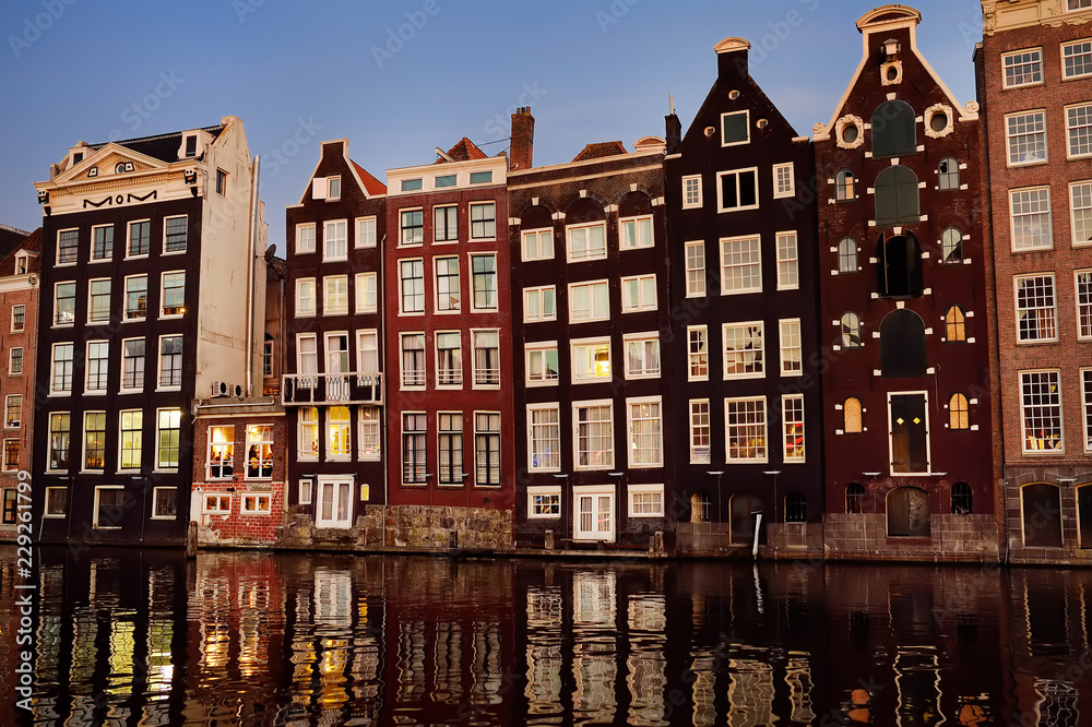 Famous dancing houses of the Damrak canal in Amsterdam on dusk