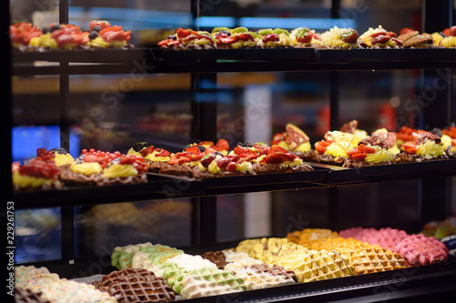 Belgian and Liege waffles with chocolate, berries, sweet sauce, cream in the window of a cafe or store