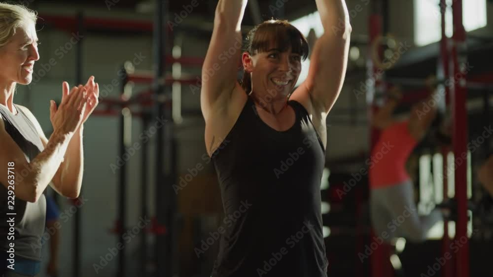 Slow motion shot of instructor encouraging woman lifting kettle bell in gymnasium / Lehi, Utah, United States