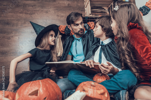 Man and Children in Costumes Reading Book Together