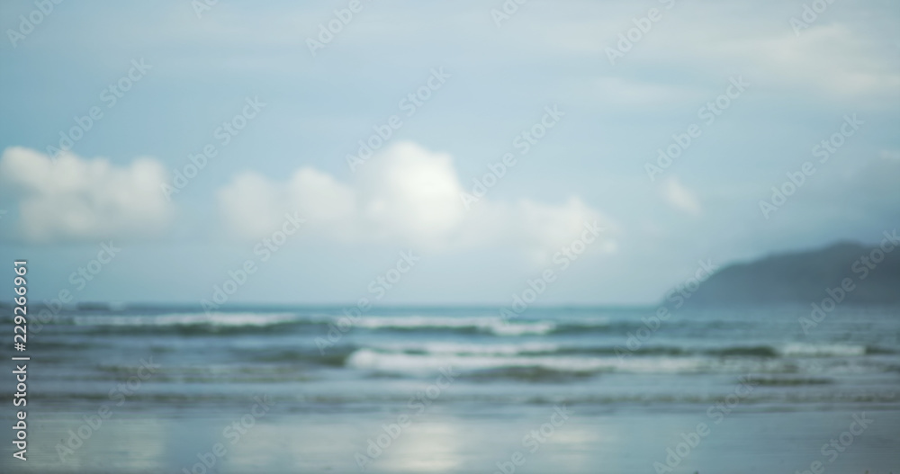 Fototapeta premium Blurred shot of beautiful clouds and low tide waves on tropical beach