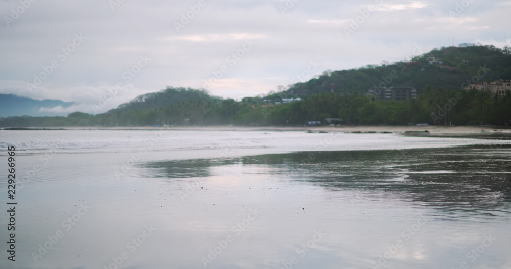 Calm low tide waves on typical Costa Rica beach with forest