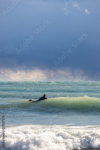 Lake Huron, Ontario, Canada - October 17, 2018: A group of Great Lakes surfers catching waves during an autumn storm.