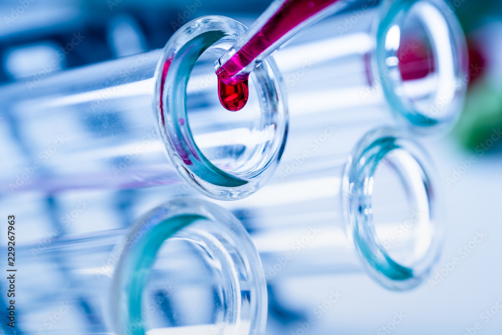 Pipette adding fluid to one of several test tubes .medical glassware. Pipette adding fluid to one of several test tubes .medical glassware.