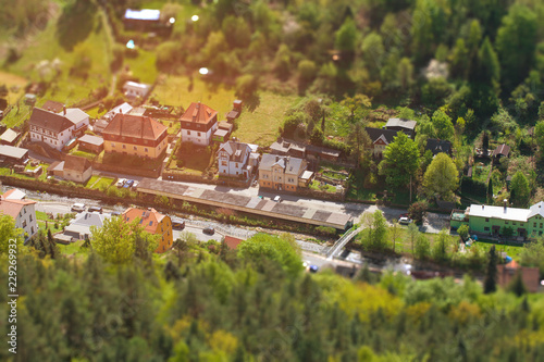 House near a stream in a forest with effect of tilt shift. The building of the suburbs near the river in miniature. Selective focus on the countryside from the height of the helicopter.