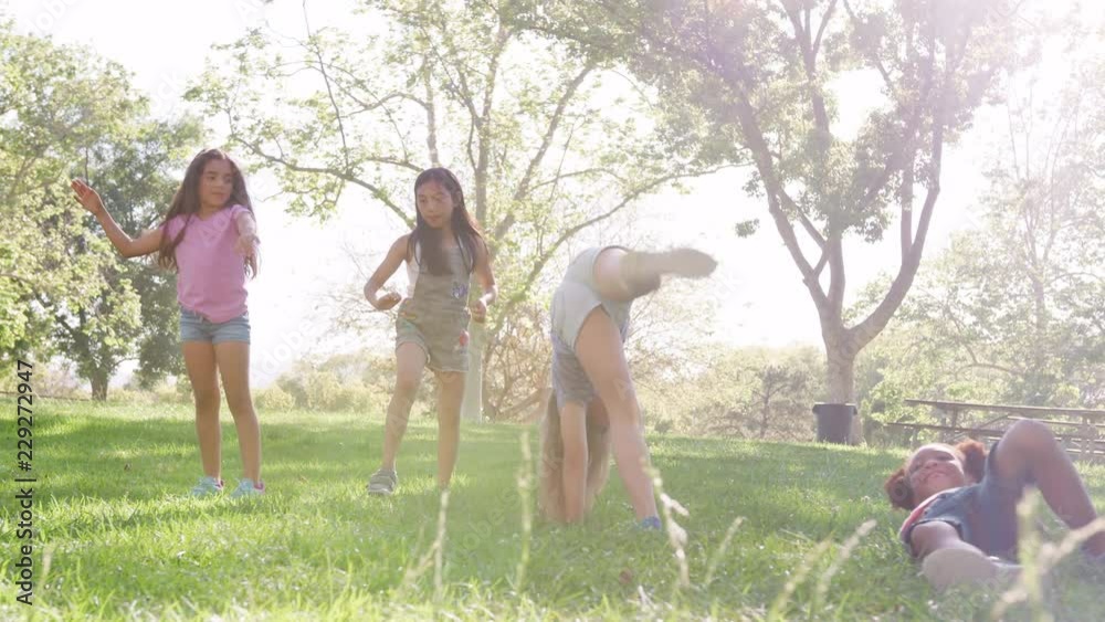 Group Of Young Girls With Friends Turning Cartwheels In Park Shot In Slow Motion
