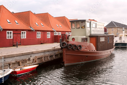 Red roofs houses near river bay with moored boats in Copenhagen, Denmark. City with water chanels