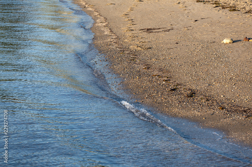 Gentle waves of Penobscot Bay lapping the beach in Maine in the summertime. photo