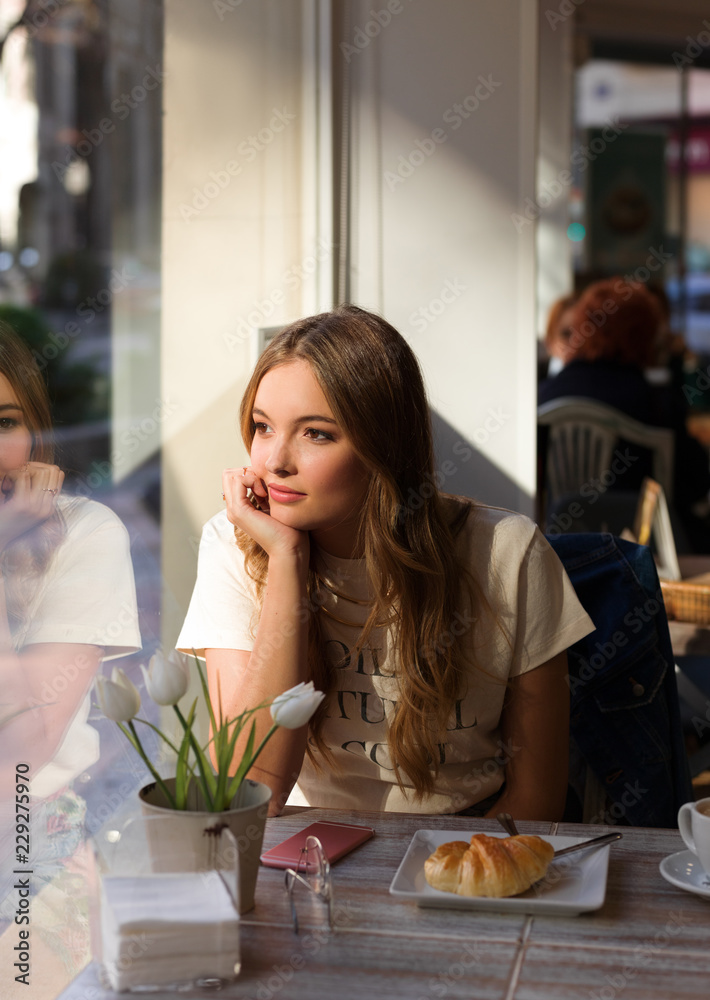 Dreaming girl sitting in cafeteria looking away Dreaming girl sitting in cafeteria looking away
