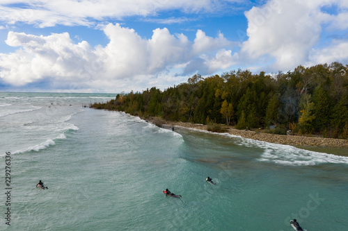 Obraz na plátně Lake Huron, Ontario, Canada - October 17, 2018: Aerial view of a group of Great Lakes surfers catching waves during an autumn storm
