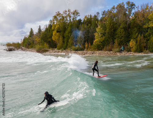 Lake Huron, Ontario, Canada - October 17, 2018: Aerial view of a group of Great Lakes surfers catching waves during an autumn storm.