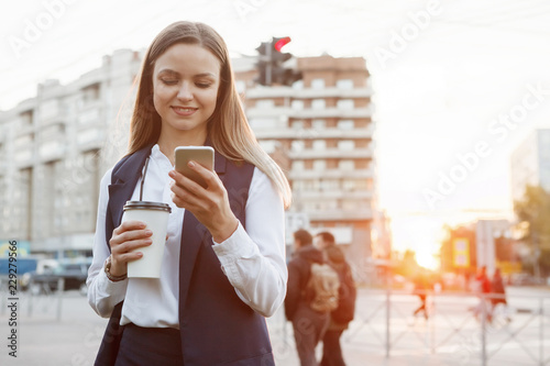 Young pretty woman with smartphone and paper coffee cup.