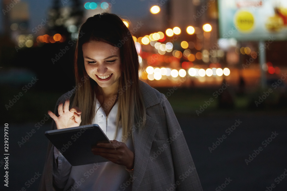 Beautiful woman with tablet outside in the night city