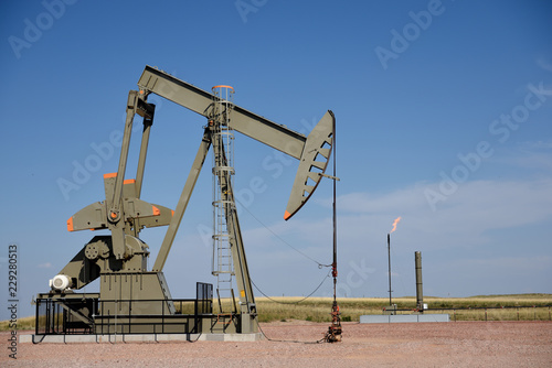 Photography Crude oil pump jack with natural gas flaring and a clear blue sky, Powder River