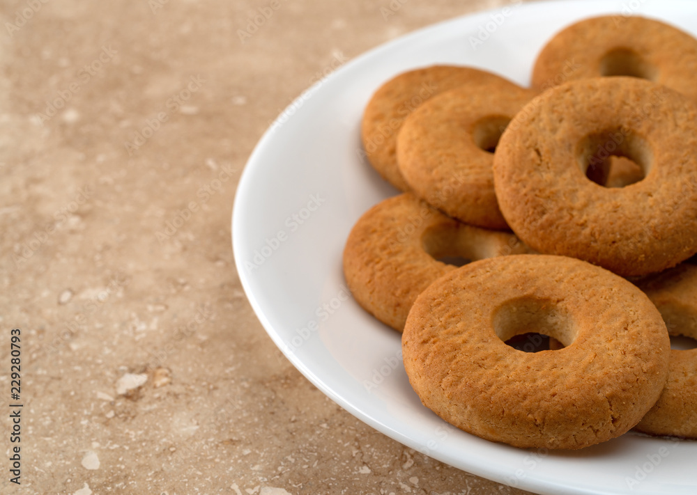 Side close view of several coconut cookies on a white plate atop a marble counter top. Side close view of several coconut cookies on a white plate atop a marble counter top.