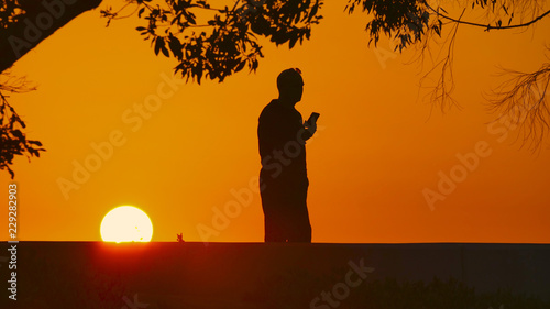 man on cell phone during sunset