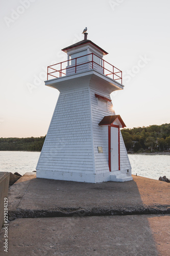 A small backlit lighthouse sitting at the end of a pier photo