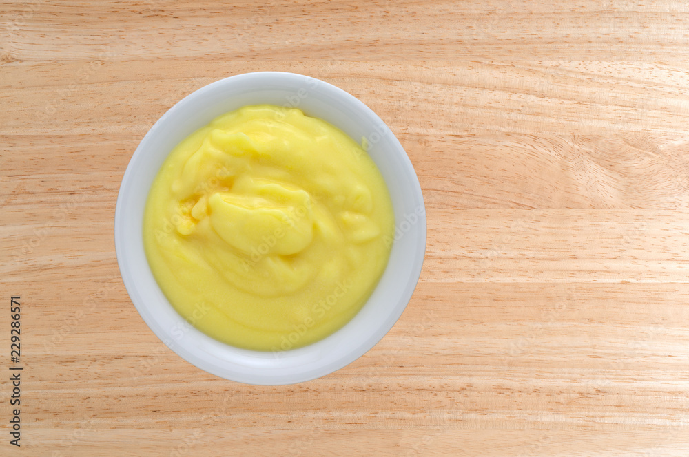 Top view of homemade banana cream pudding in a small bowl atop a wood table. Top view of homemade banana cream pudding in a small bowl atop a wood table.