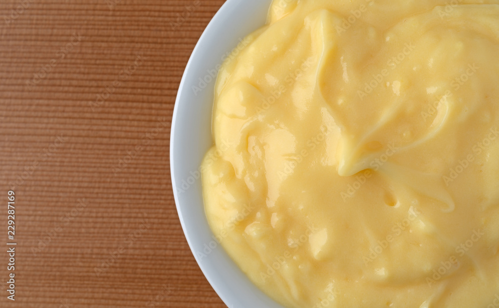 Top close view of homemade banana cream pudding in a white dish atop a wood table illuminated with window light. Top close view of homemade banana cream pudding in a white dish atop a wood table illuminated with window light.