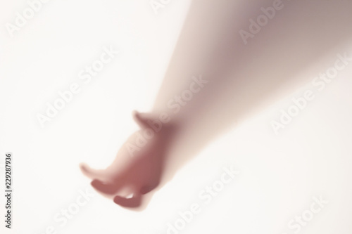The concept of the shadow of hand behind frosted glass illuminated from behind.