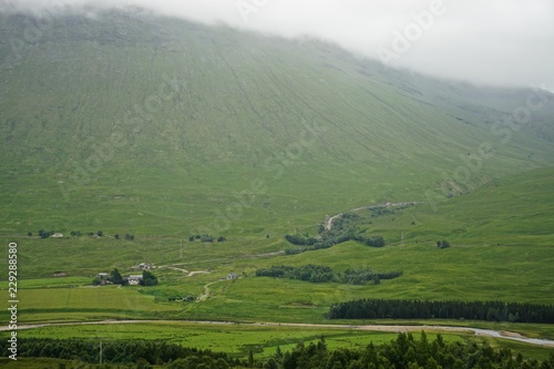 Clouds and mist over lush farmland with a stream running through it, in the West Highlands of Scotland.