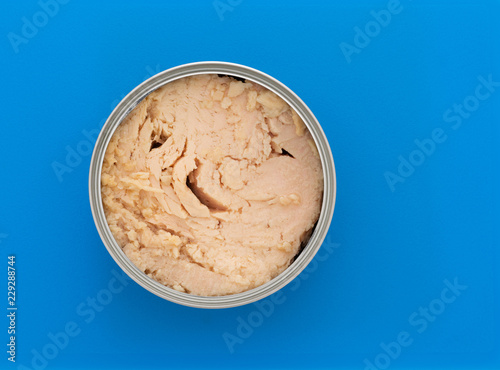 Canvas Print Top view of an opened can of solid white albacore tuna in olive oil atop a blue plastic cutting board