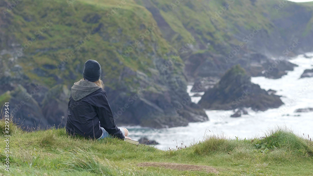 Fototapeta premium Girl relaxes on the top of the cliffs
