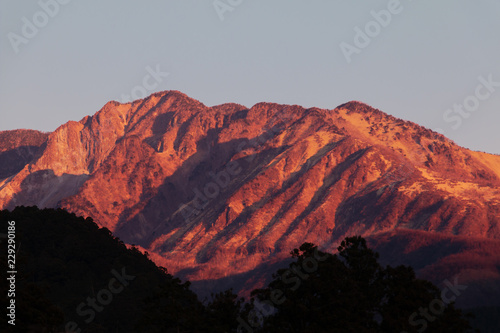 朝日を浴びて赤く染まる山