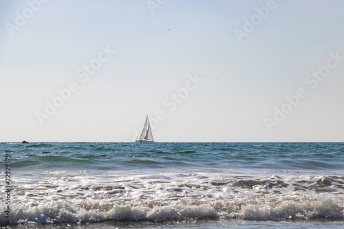 Sailboat on horizon of an empty blue ocean