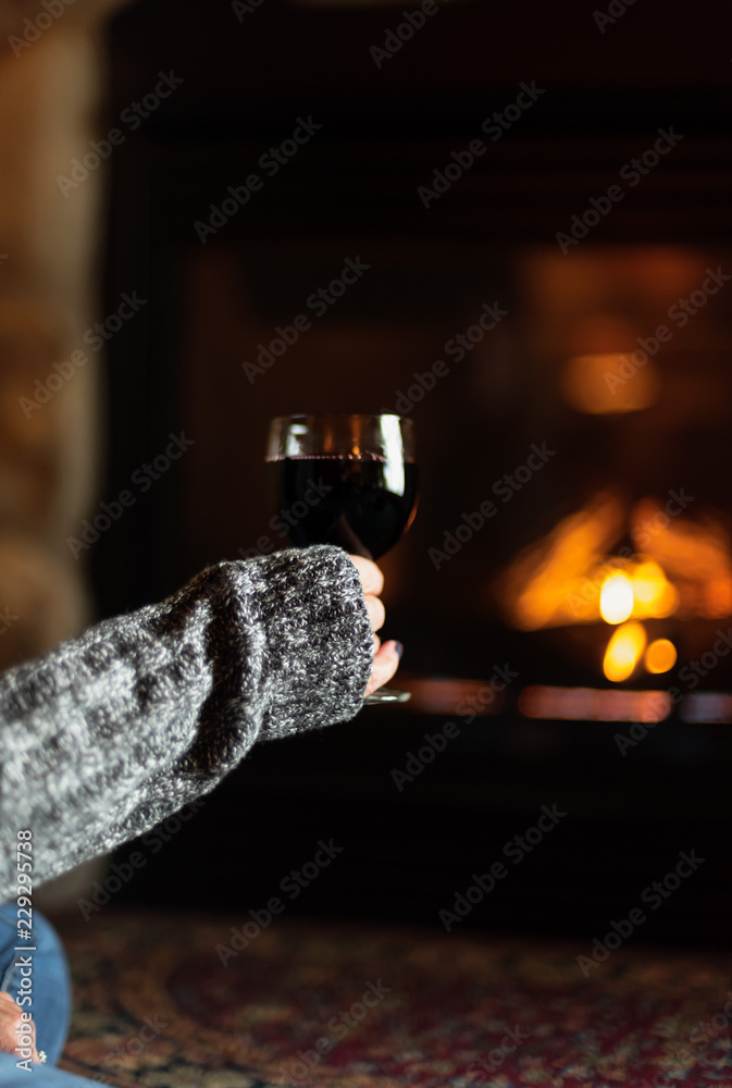 Φωτογραφία woman sitting by fieldstone fireplace with glass of wine