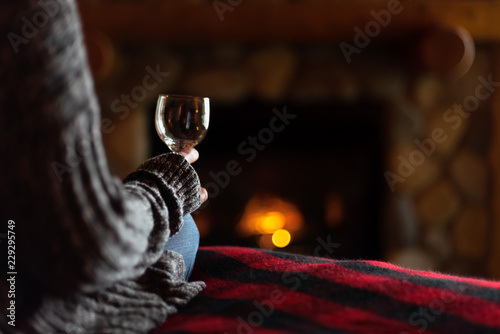 sitting in cozy cabin by fieldstone fireplace with glass of wine