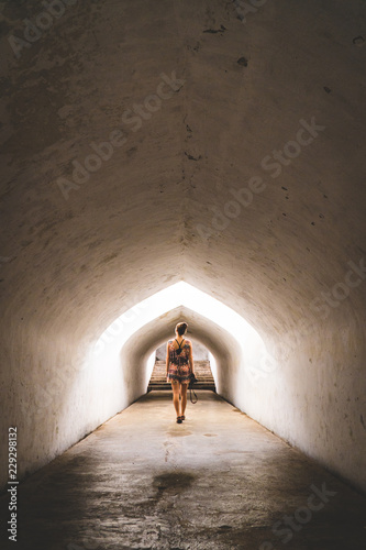 A young woman walking through a tunnel in an ancient palace