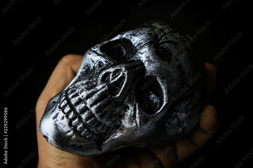 Skull Halloween dark scary horror story ideas concept with human hand isolated on black background