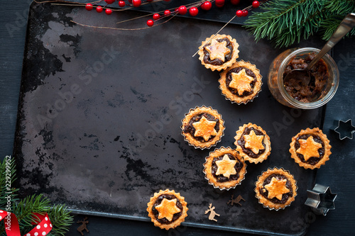 Freshly baked mince pies - Traditional Christmas fruit tarts - on a vintage baking tray with festive Xmas decorations photo