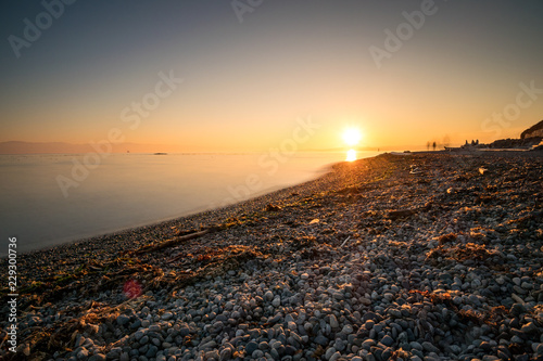Fototapeta Naklejka Na Ścianę i Meble -  sunset over the horizon with orange light illuminated close by beach