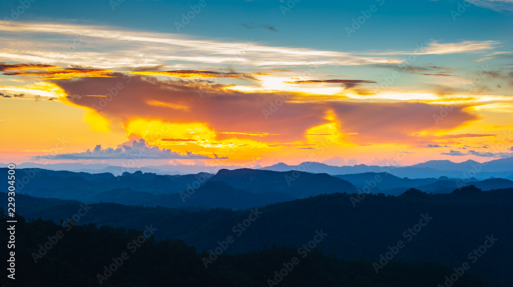 Landscape scene of colorfull sunset sky with mountain range and forest.