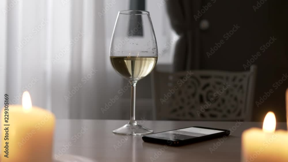 Young woman drinks white wine alone, focus on glass, with mobile phone Young woman drinks white wine alone, focus on glass, with mobile phone