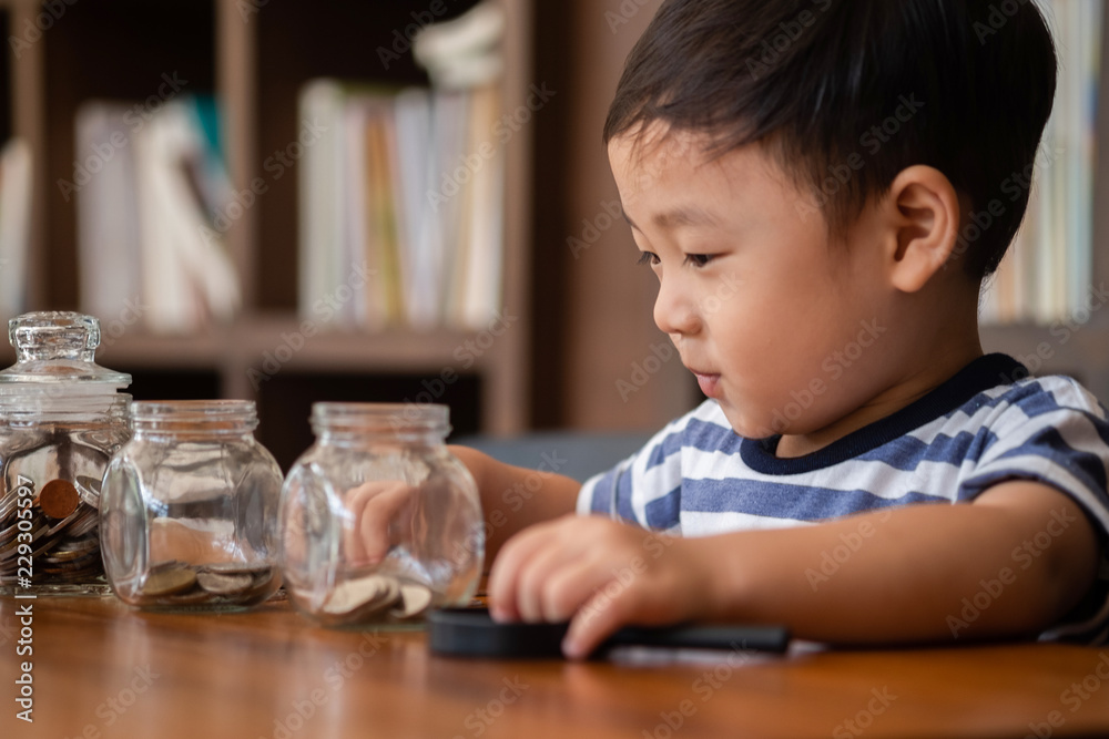 cute boy putting money coins in glass,saving money concept cute boy putting money coins in glass,saving money concept
