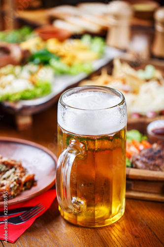 A glass of light beer on the background of a table with snacks.