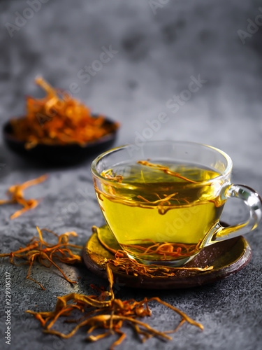 Dried cordyceps militaris mushroom with cup. cup of cordyceps (chong cao) tea on old and crack wooden surface, Healthy beverage concept. chinese herb.