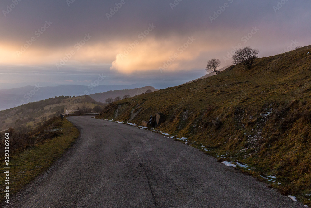 Mountain road with mist filling a valley in the background and warm sunset colors